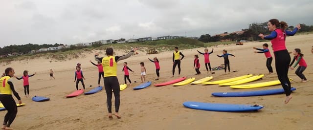 Alumnos y monitores calentando en la playa antes de entrar al agua